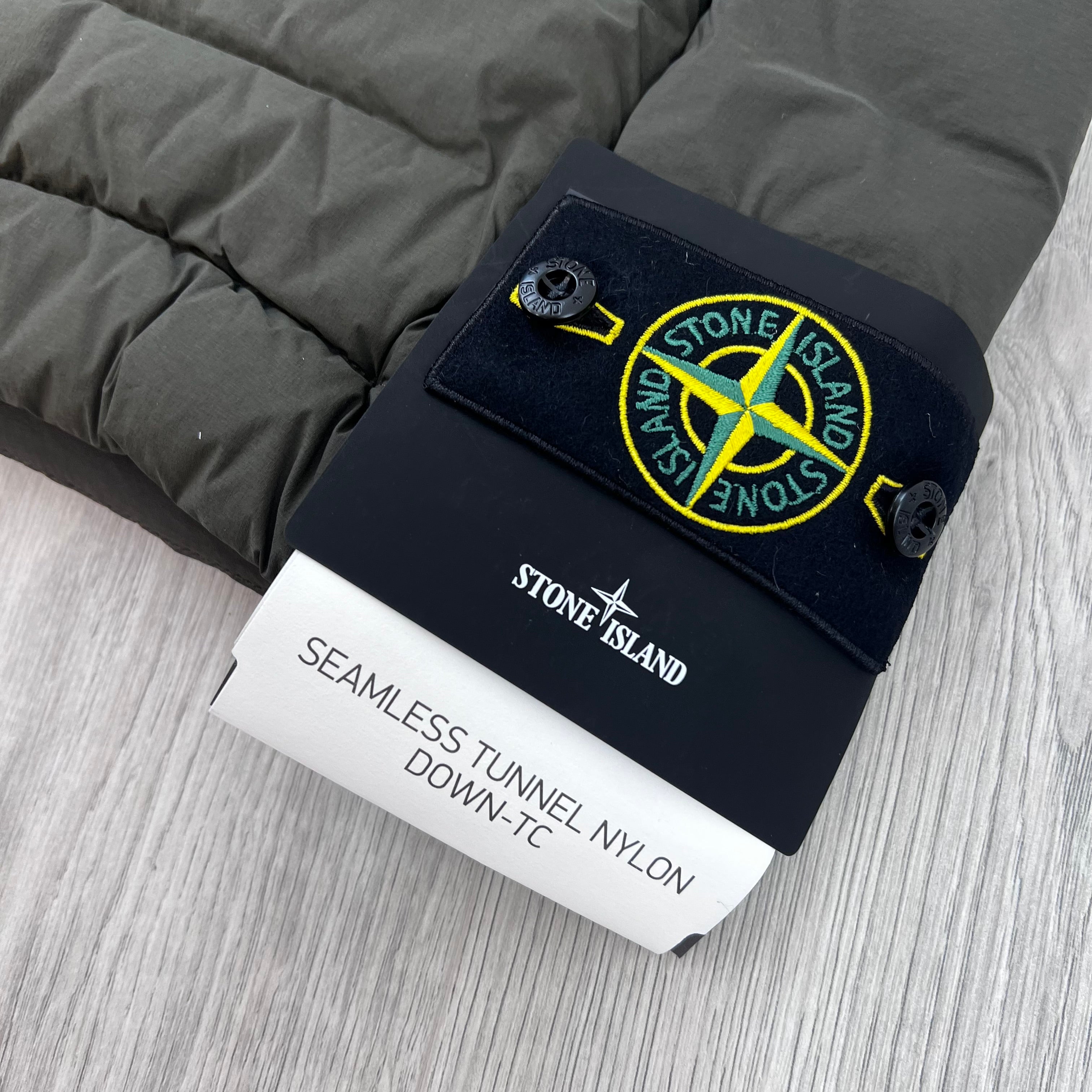 A close view of the logo badge on a Stone Island Seamless Tunnel Nylon Down-TC Down Gilet in Coal Grey.