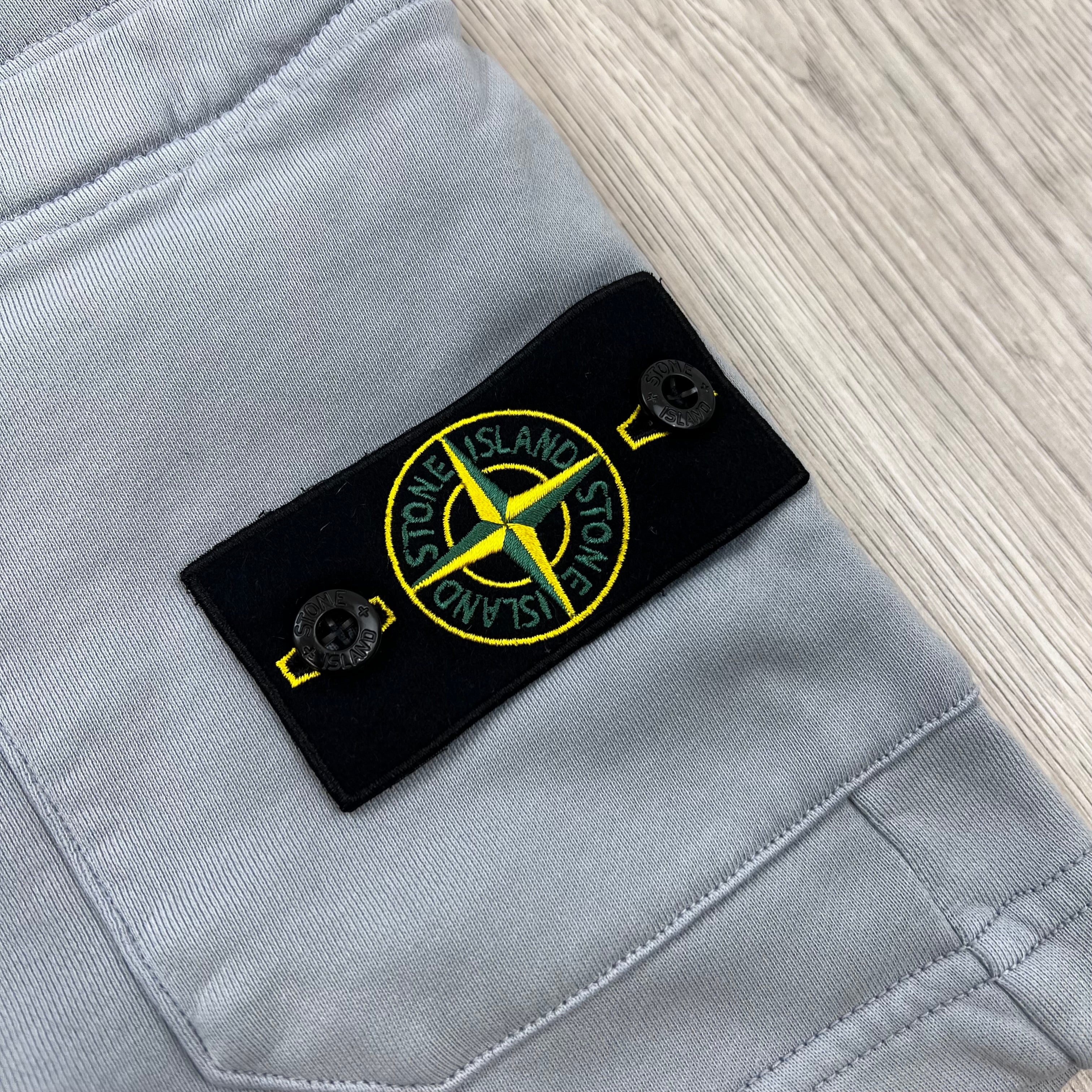 A close up view of the compass badge on the Stone Island Jersey Shorts in Ash Grey.