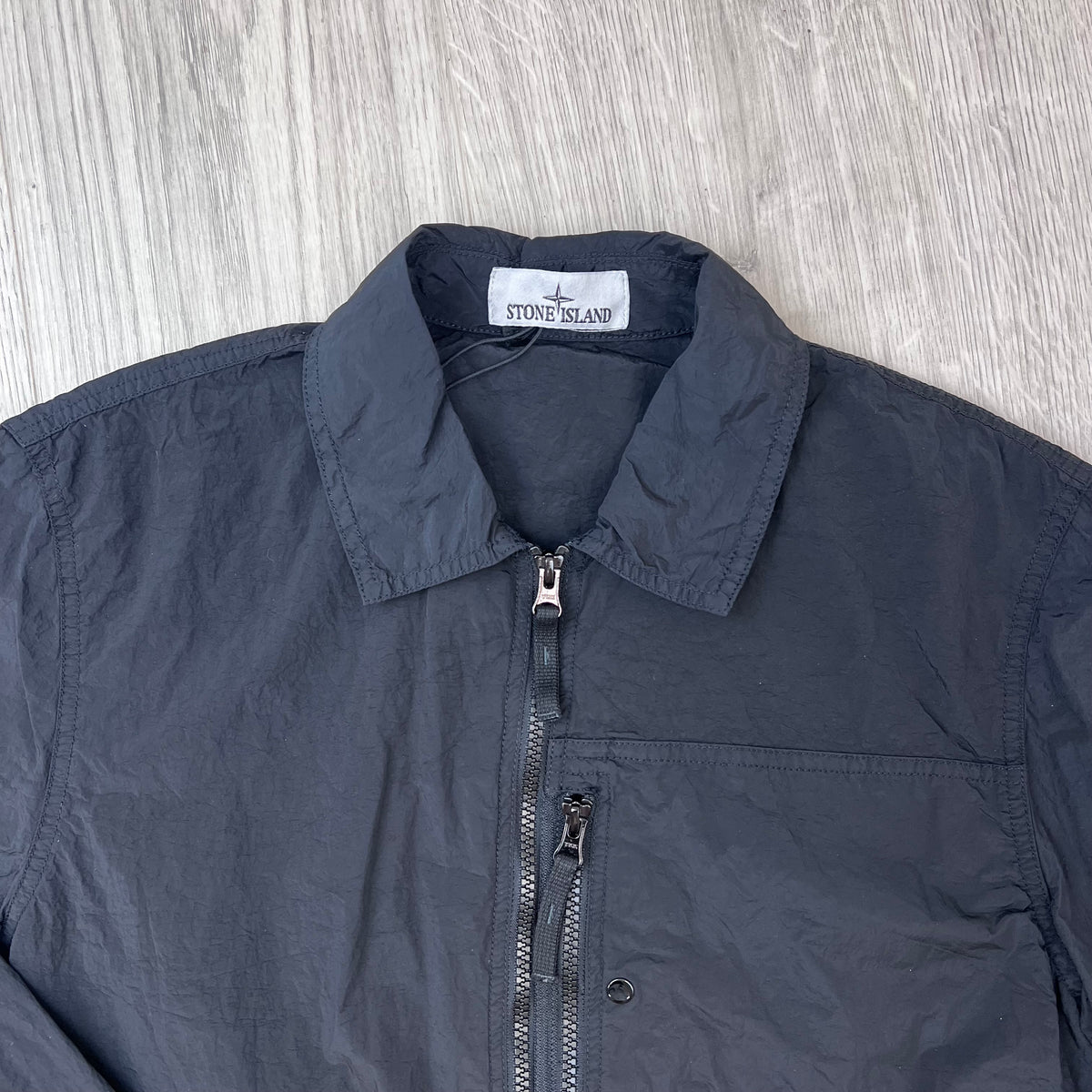 A close up view of the classic collar and neck label on a Stone Island Nylon Metal Overshirt in Black.
