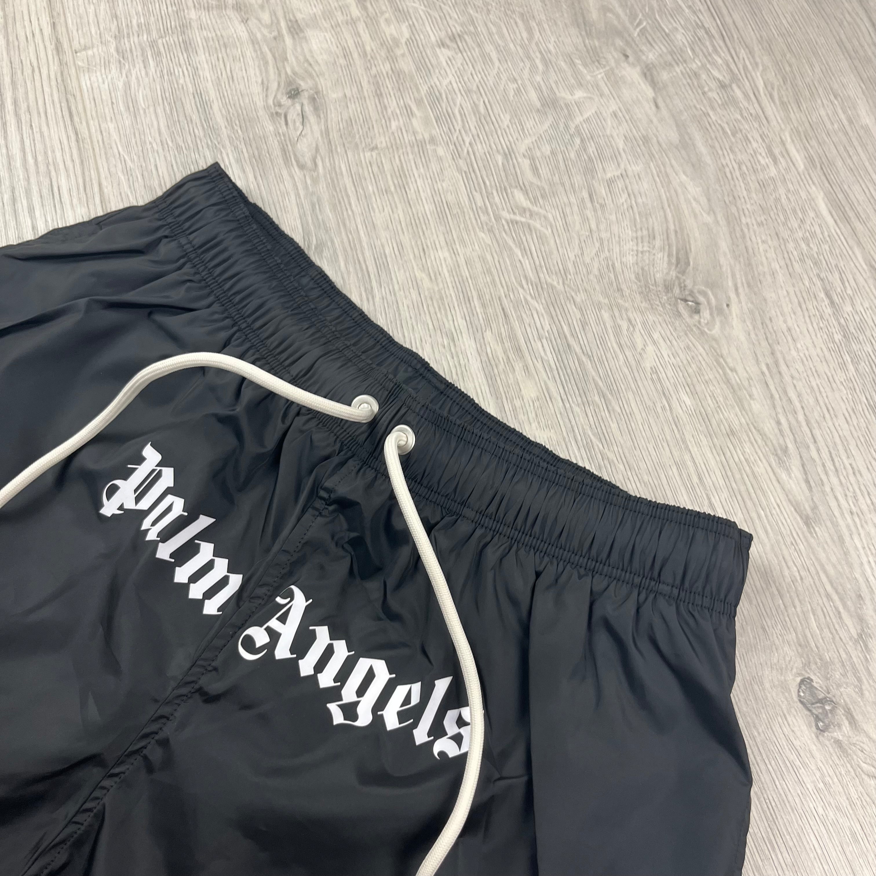 Palm Angels Gothic Logo Swim Shorts in Black. On sale at Open Attire.