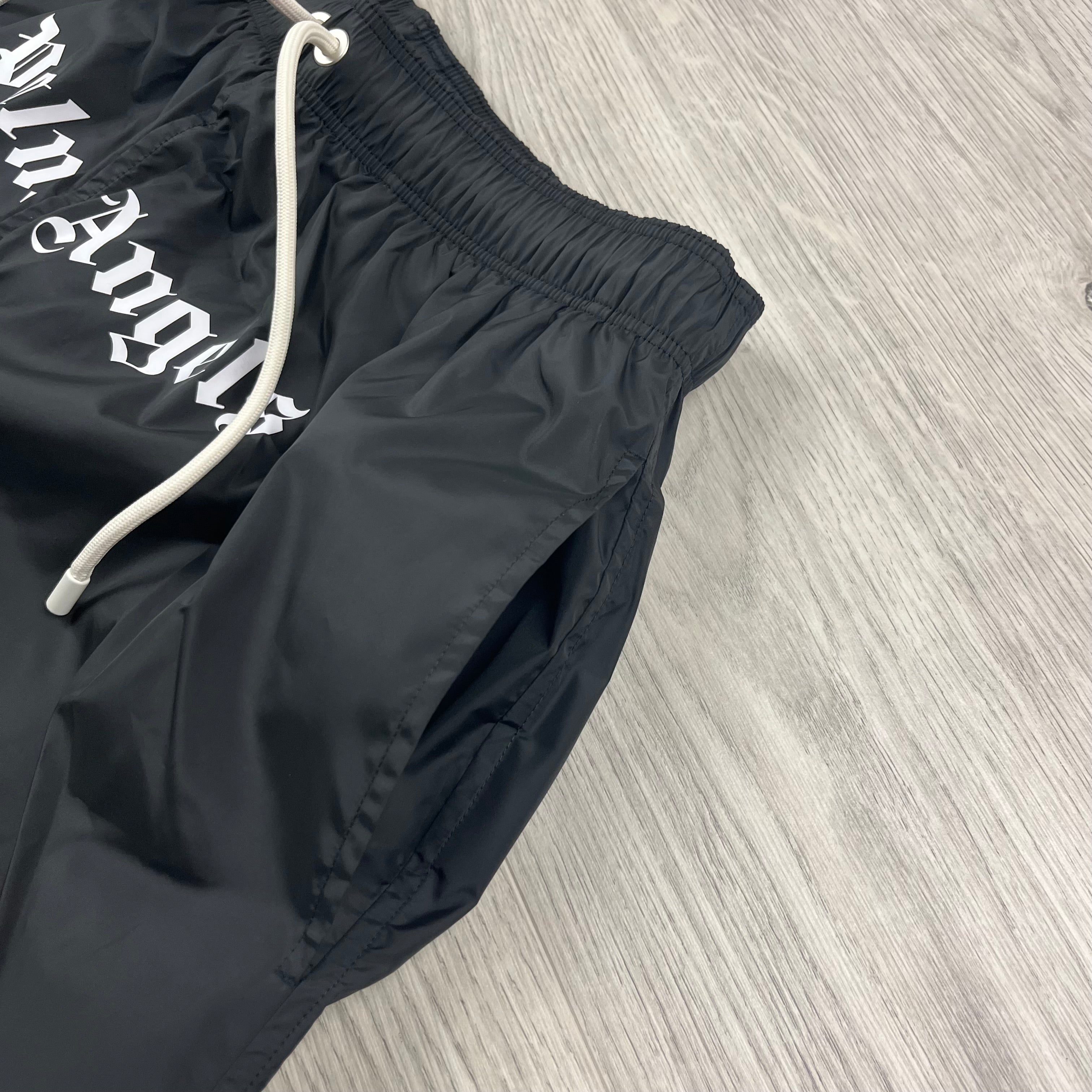 Palm Angels Gothic Logo Swim Shorts in Black. On sale at Open Attire.