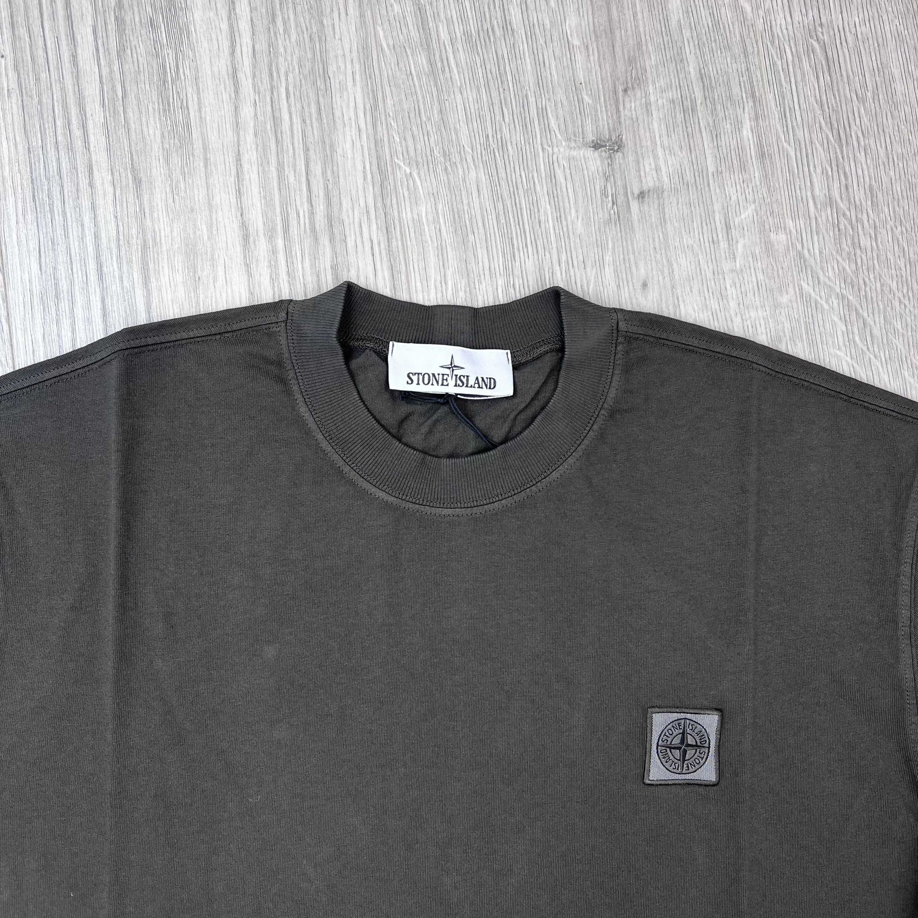 A close up view of the crewneck collar and an embroidered patch logo on a Stone Island Combed Organic Patch T-Shirt in Coal Grey.