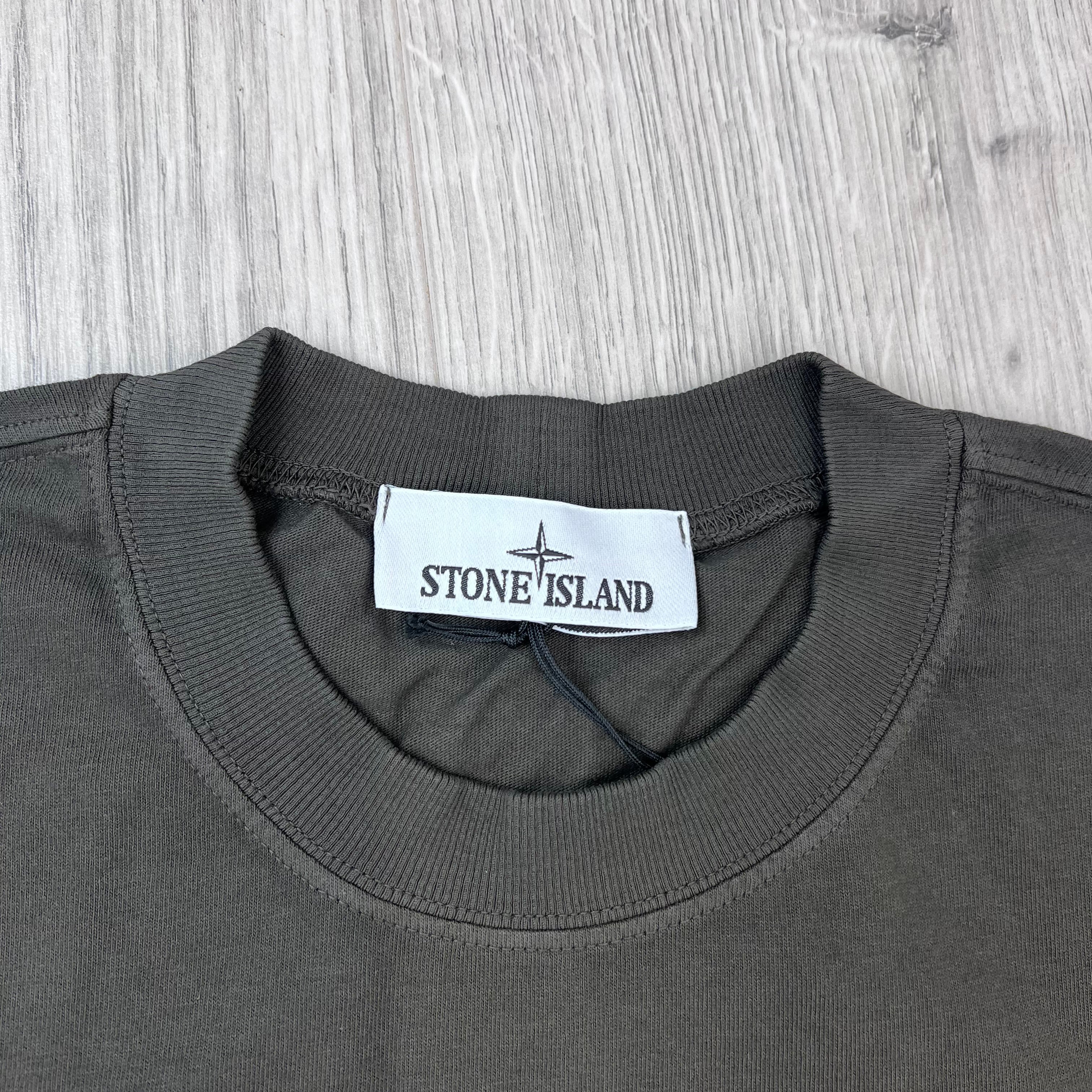 A close up view of the crewneck collar on a Stone Island Combed Organic Patch T-Shirt in Coal Grey. 