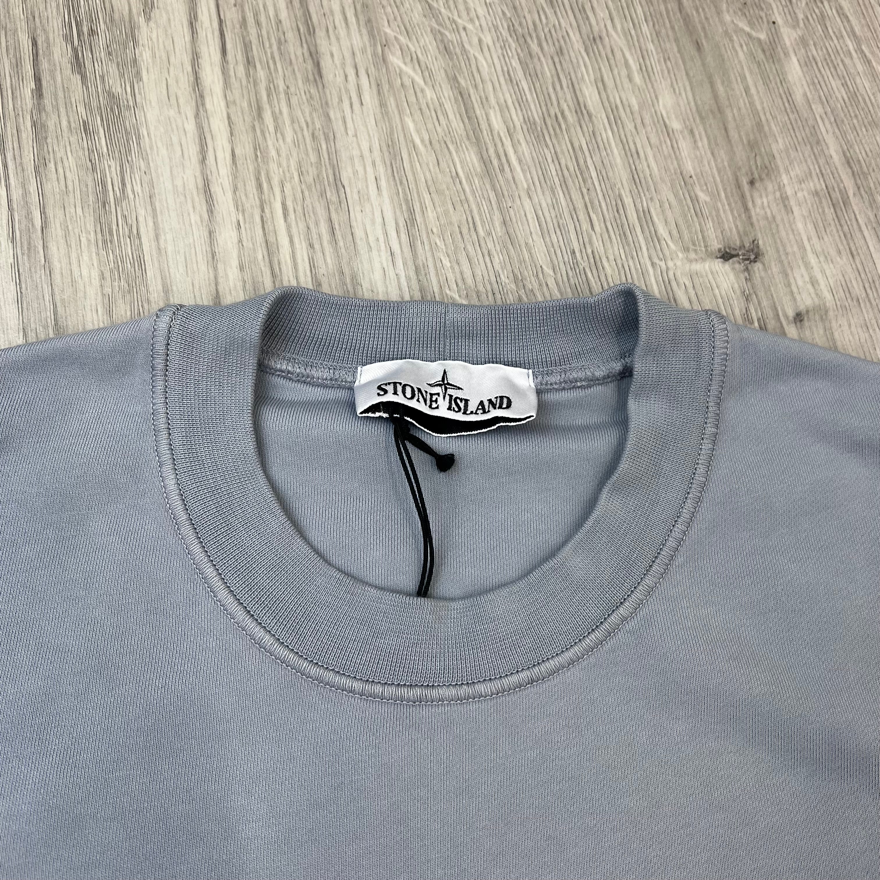 A close up view of the crewneck and label on a Stone Island Crewneck Sweatshirt in Ash Grey.