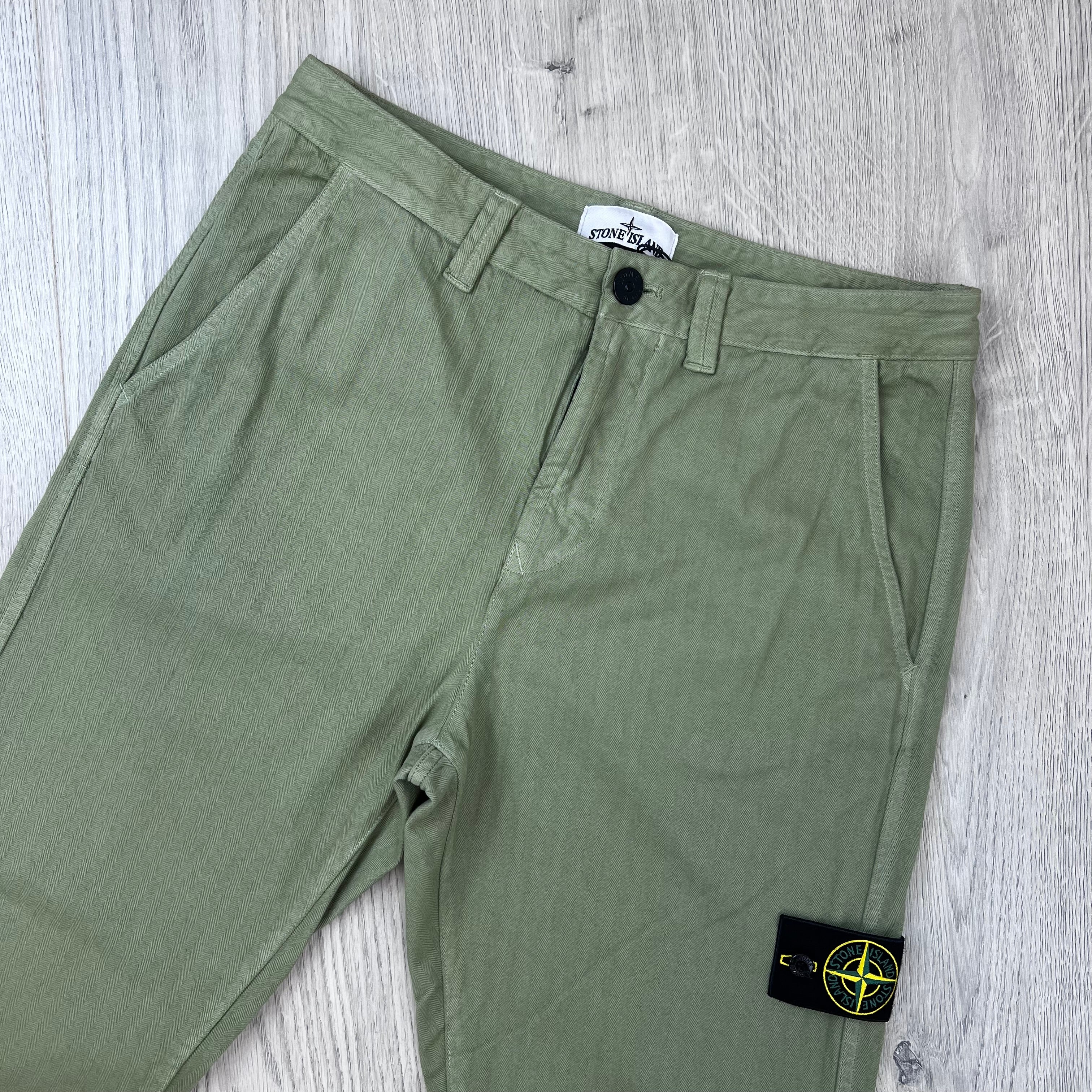 Front view of the waist closure on the Stone Island Cotton Herringbone Chino Trousers in Laurel Green.