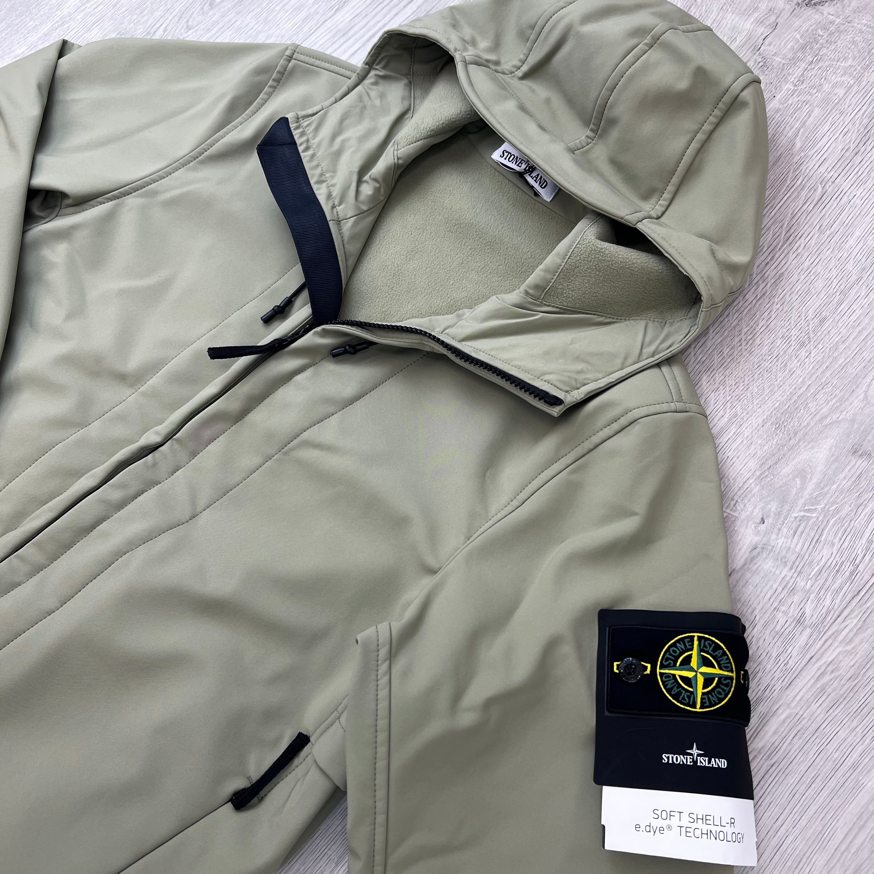 Angled view of the badge logo and hood on a Stone Island Soft Shell-R_e.dye® Jacket in Laurel Green.
