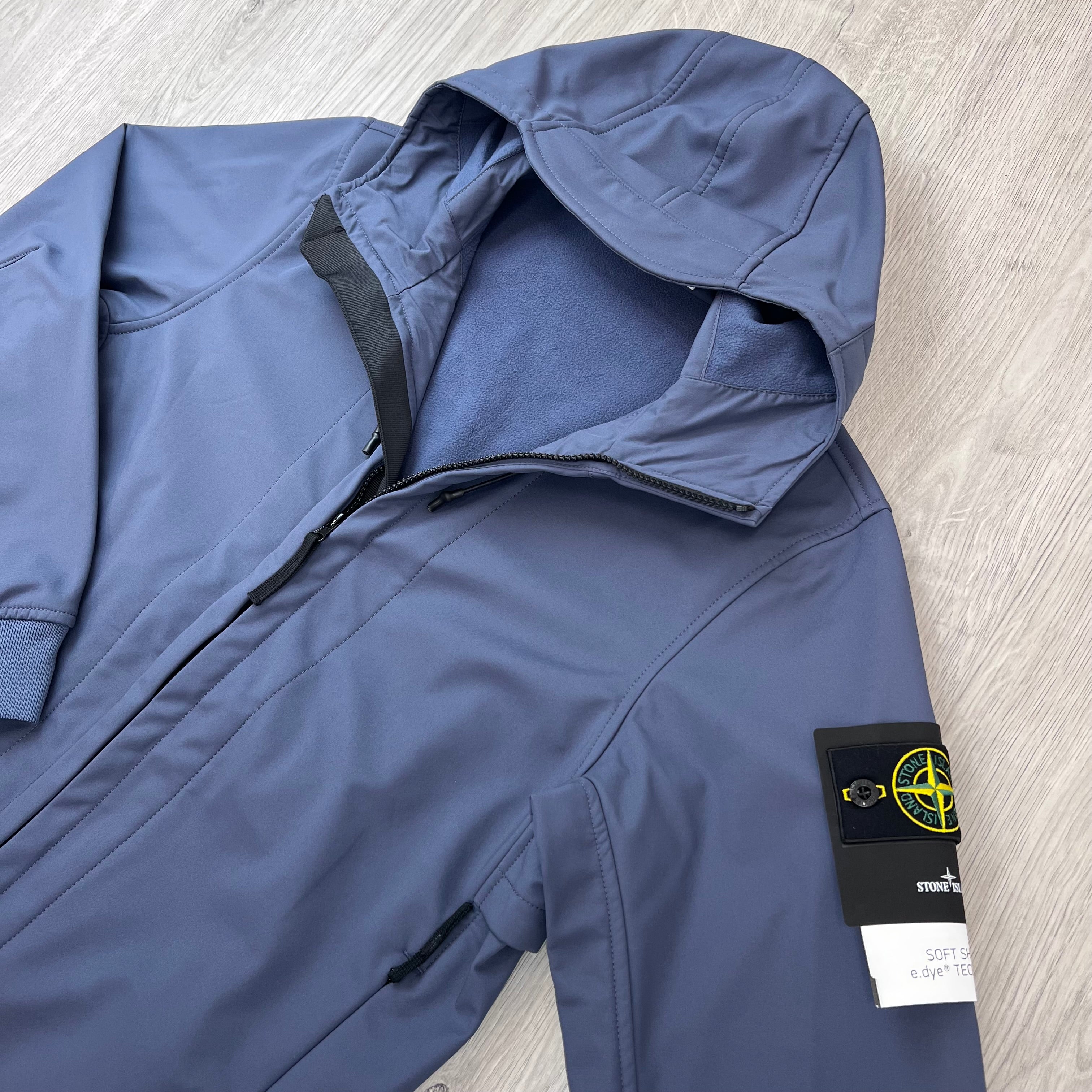 Angled view of the badge logo and hood on a Stone Island Soft Shell-R_e.dye® Jacket in Slate Blue.