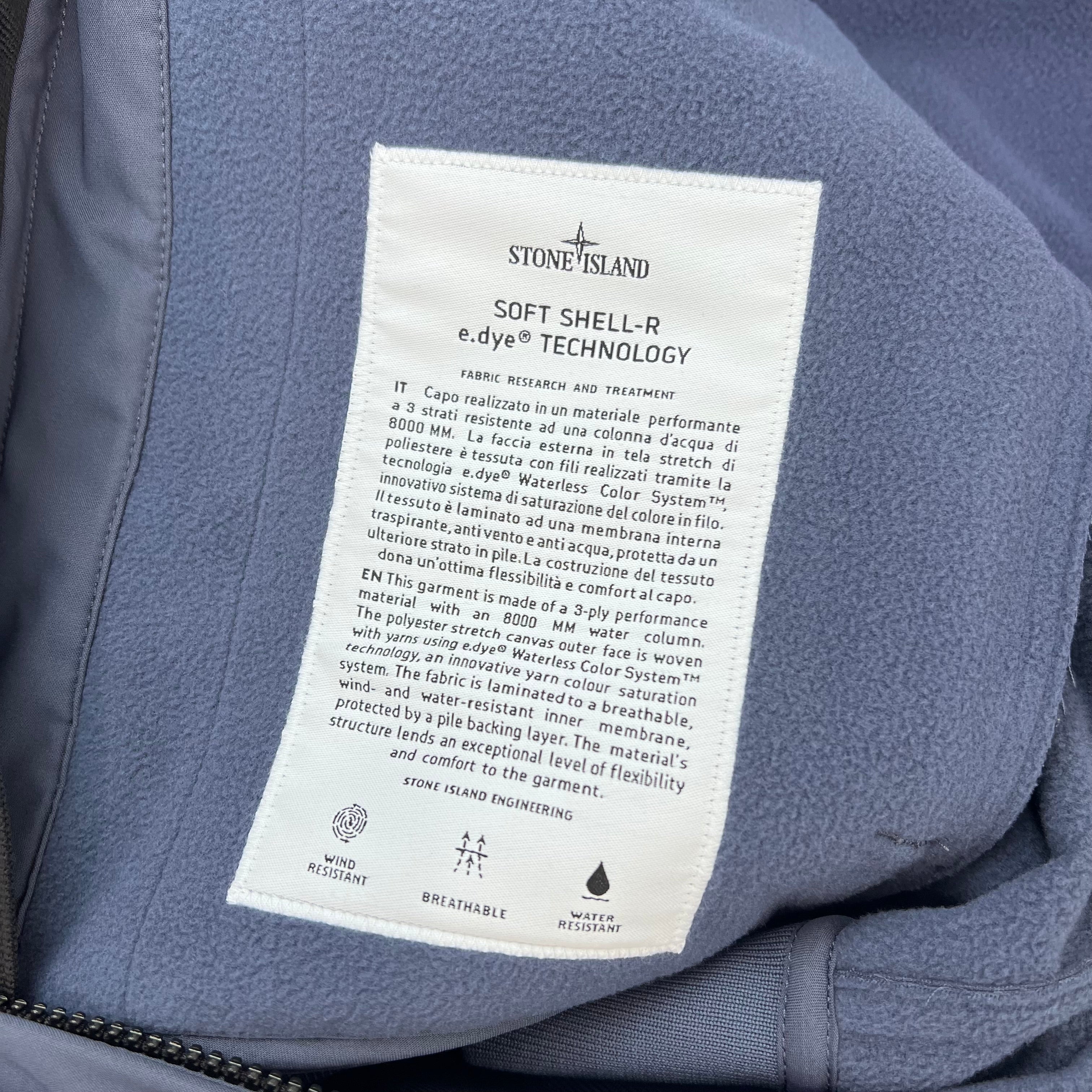 A close up view of the engineering label on the inside of a Stone Island Soft Shell-R_e.dye® Jacket in Slate Blue.
